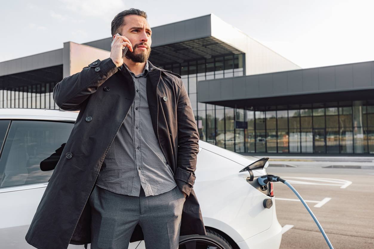 Employé branchant une voiture électrique sur une borne en entreprise
